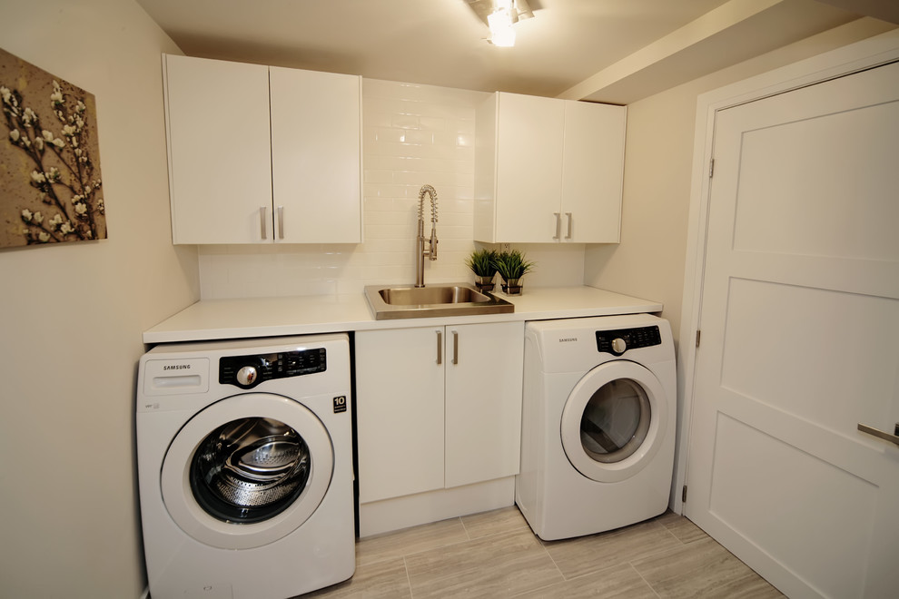 Inspiration for a mid-sized modern single-wall dedicated laundry room in Toronto with white cabinets, beige walls, a side-by-side washer and dryer, flat-panel cabinets, quartzite benchtops, a drop-in sink, porcelain floors, beige floor and white benchtop.