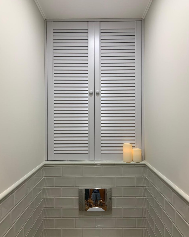 This is an example of a small contemporary powder room in Moscow with louvered cabinets, grey cabinets, green tile and white walls.