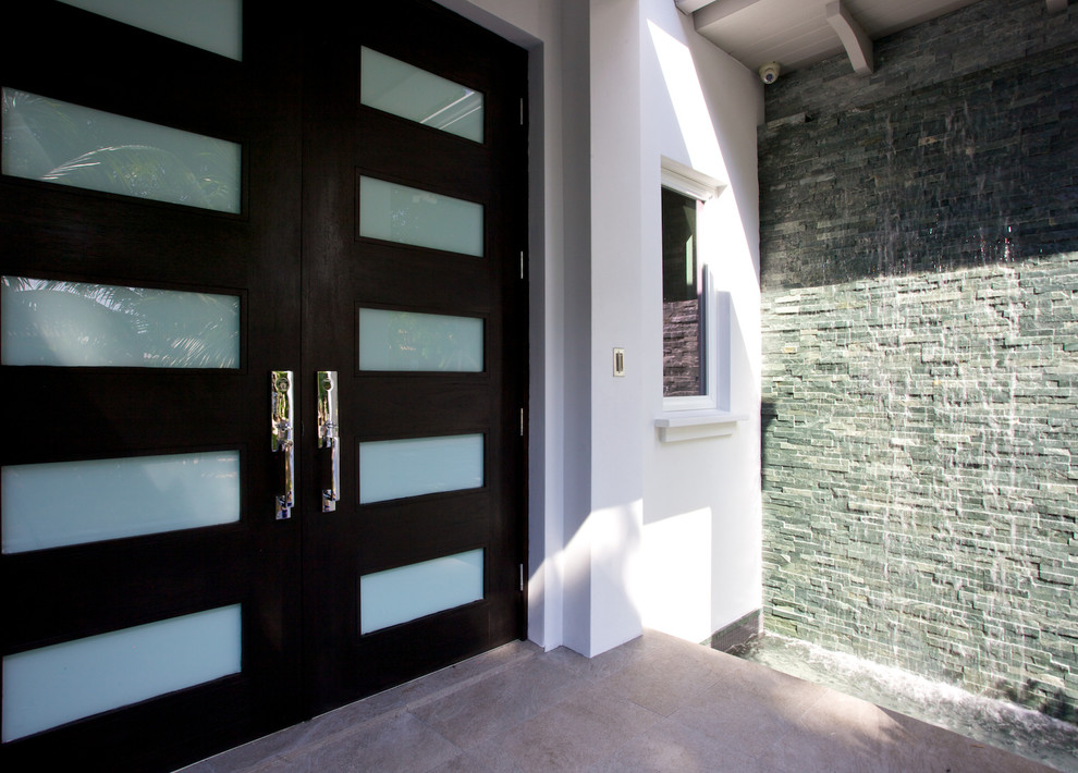 Design ideas for a mid-sized modern front door in Miami with brown walls, ceramic floors, a double front door and a dark wood front door.