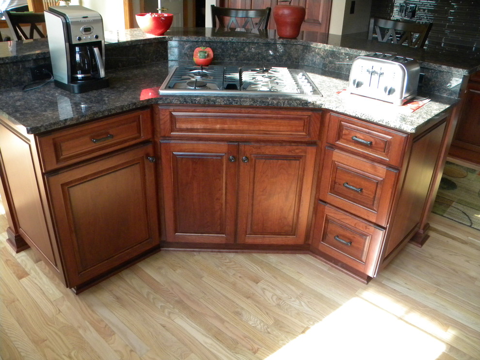 Inspiration for a mid-sized transitional u-shaped light wood floor eat-in kitchen remodel with an undermount sink, raised-panel cabinets, medium tone wood cabinets, granite countertops, multicolored backsplash, stone tile backsplash, stainless steel appliances and an island