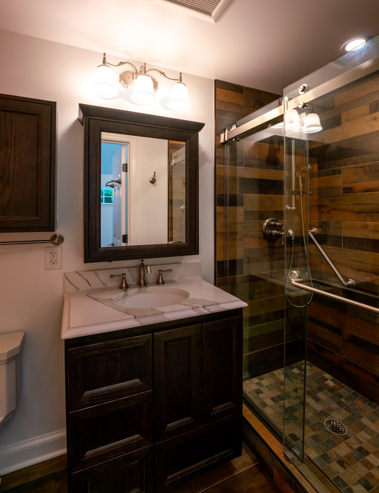 Inspiration for a mid-sized arts and crafts 3/4 bathroom in DC Metro with brown cabinets, brown tile, wood-look tile, white walls, dark hardwood floors, marble benchtops, brown floor, a sliding shower screen, white benchtops, a single vanity and a built-in vanity.