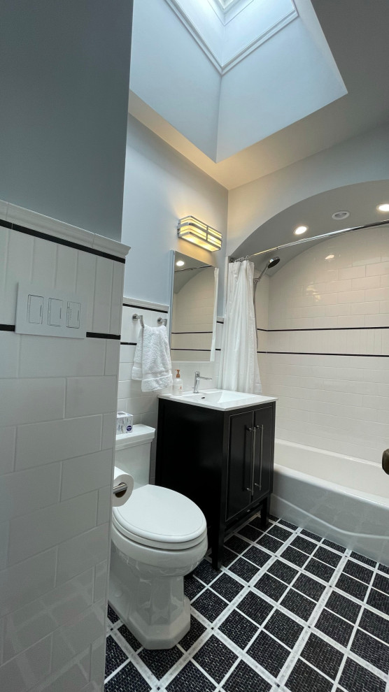 Small traditional bathroom in Philadelphia with flat-panel cabinets, black cabinets, an alcove bath, a shower/bath combination, a two-piece toilet, white tiles, porcelain tiles, blue walls, marble flooring, an integrated sink, solid surface worktops, black floors, a shower curtain, white worktops, a wall niche, a single sink, a freestanding vanity unit, a vaulted ceiling and wainscoting.