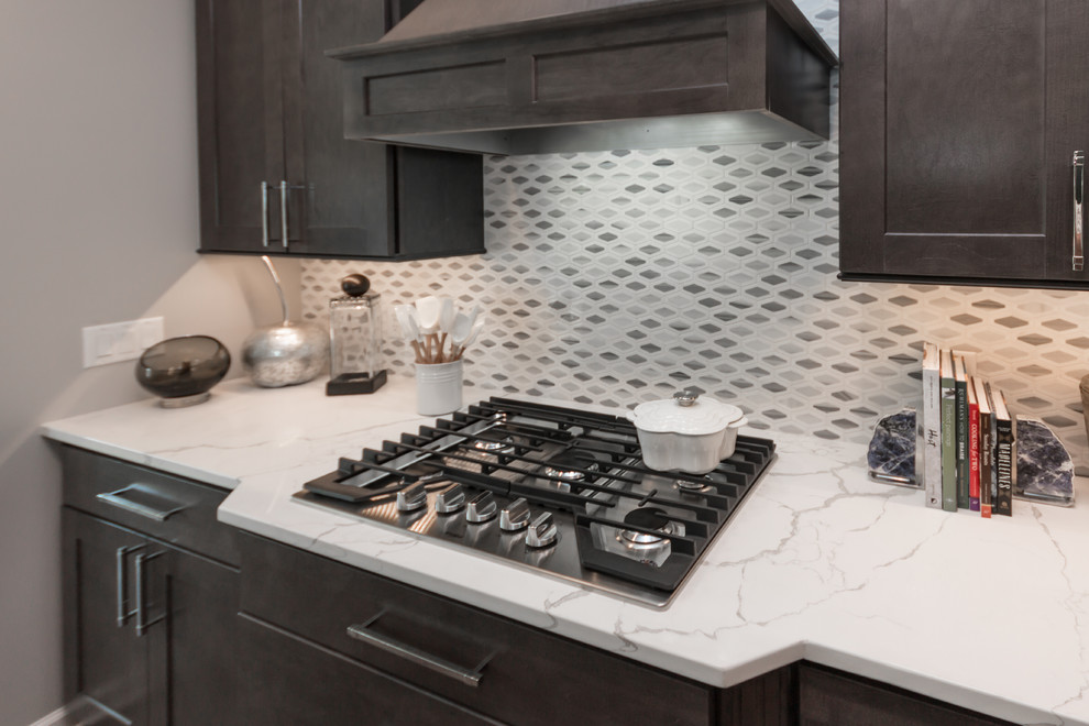 Design ideas for a mid-sized transitional open plan kitchen in Milwaukee with an undermount sink, shaker cabinets, grey cabinets, quartz benchtops, white splashback, marble splashback, stainless steel appliances, medium hardwood floors, with island, brown floor and white benchtop.