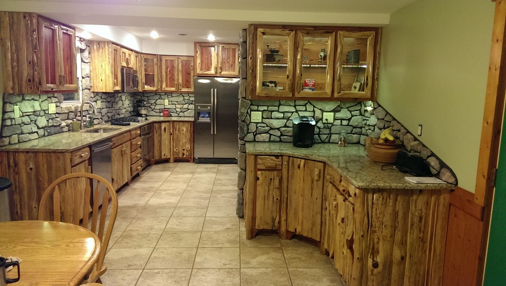 Eat-in kitchen - small rustic u-shaped ceramic tile eat-in kitchen idea with a double-bowl sink, shaker cabinets, distressed cabinets, granite countertops, gray backsplash, stone slab backsplash, stainless steel appliances and an island