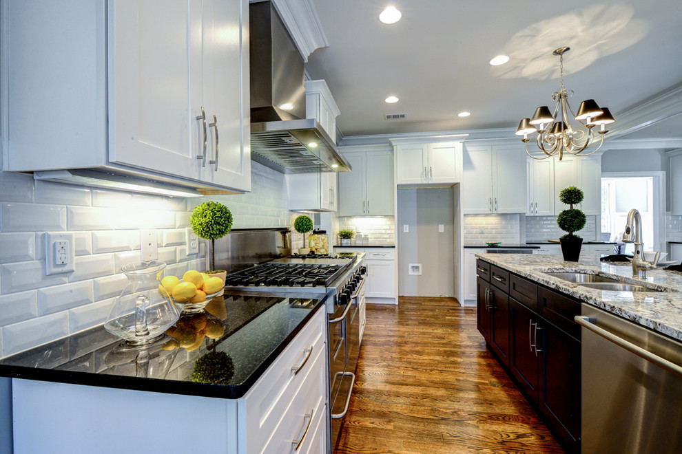 This is an example of a large traditional l-shaped open plan kitchen in Atlanta with a double-bowl sink, flat-panel cabinets, white cabinets, granite benchtops, white splashback, subway tile splashback, stainless steel appliances, medium hardwood floors and with island.