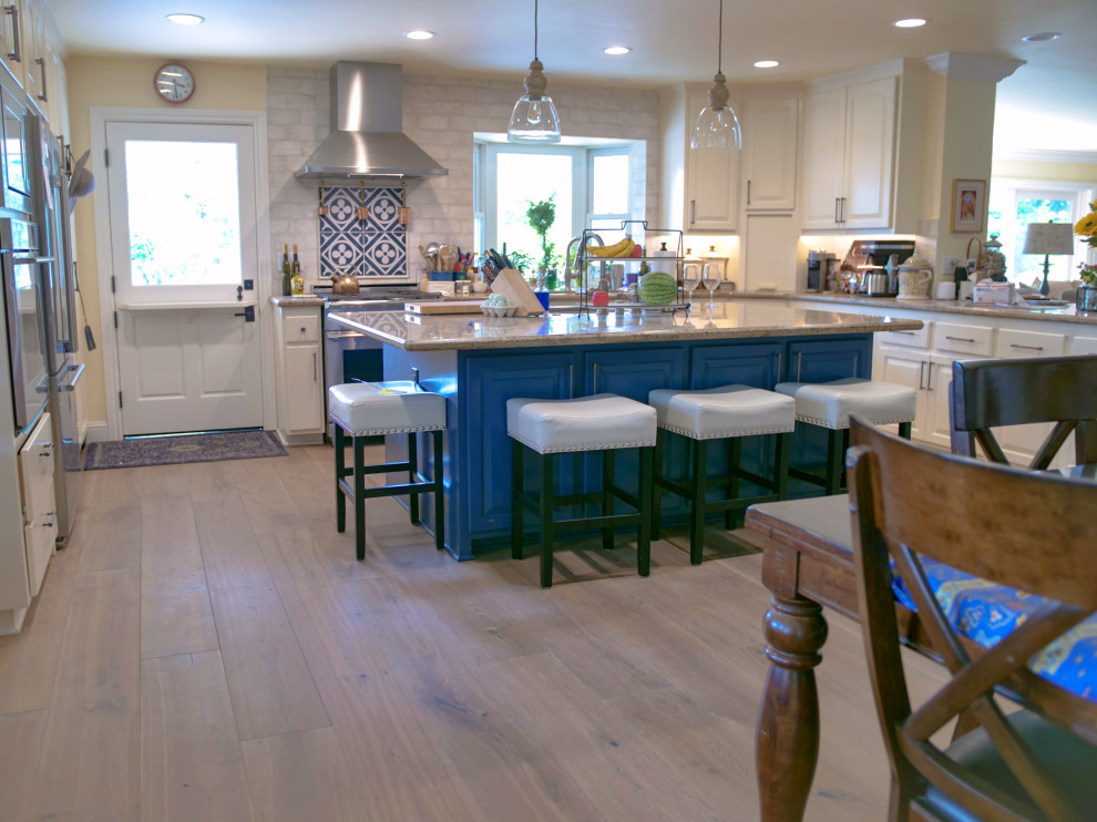 Mid-sized country u-shaped eat-in kitchen in Sacramento with beaded inset cabinets, white cabinets, granite benchtops, beige splashback, brick splashback, stainless steel appliances, medium hardwood floors, with island, brown floor and beige benchtop.