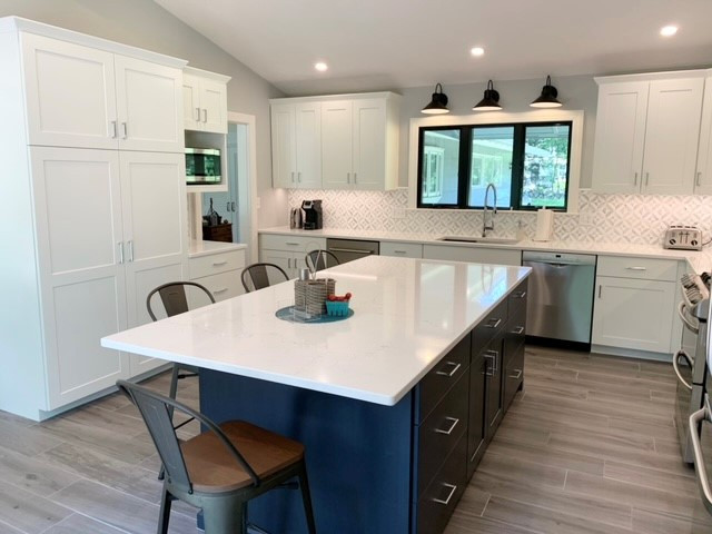 Eat-in kitchen - mid-sized modern l-shaped porcelain tile and gray floor eat-in kitchen idea in Boston with an undermount sink, recessed-panel cabinets, white cabinets, quartz countertops, porcelain backsplash, stainless steel appliances, an island and white countertops