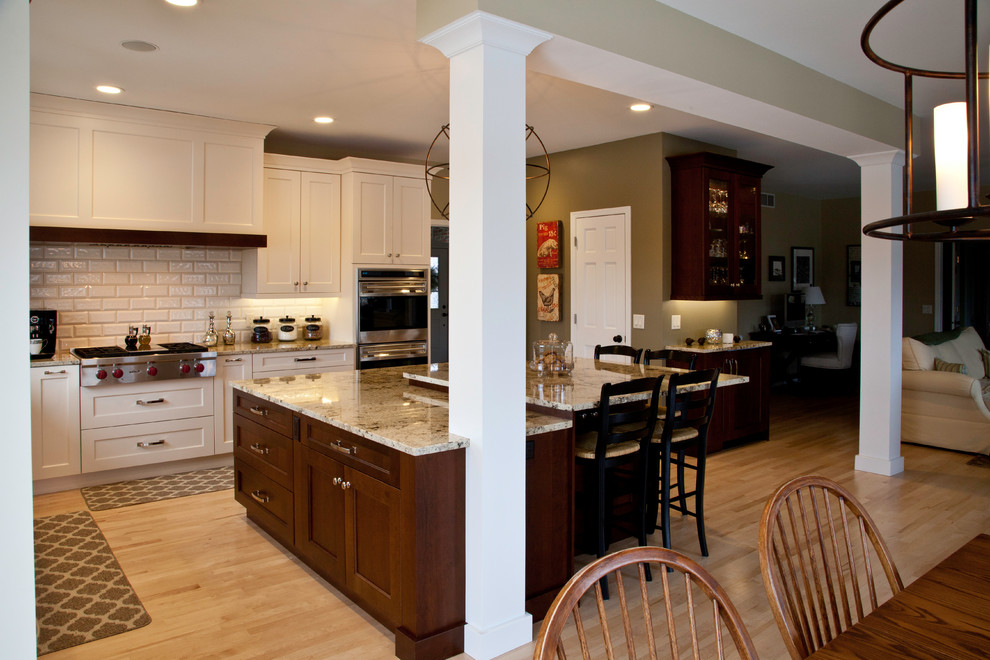 Inspiration for a large transitional l-shaped light wood floor and brown floor open concept kitchen remodel with an undermount sink, shaker cabinets, white cabinets, granite countertops, white backsplash, subway tile backsplash, paneled appliances and an island