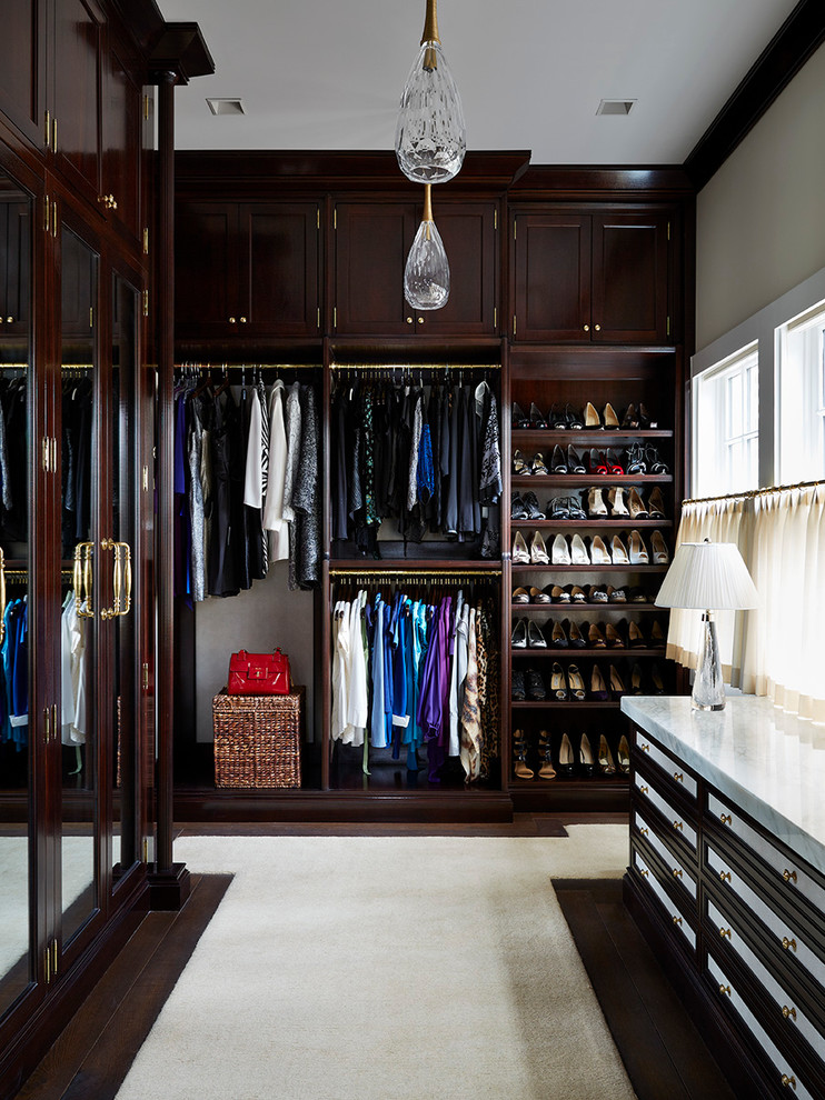 This is an example of an expansive traditional gender-neutral walk-in wardrobe in Jacksonville with dark wood cabinets, dark hardwood floors and recessed-panel cabinets.