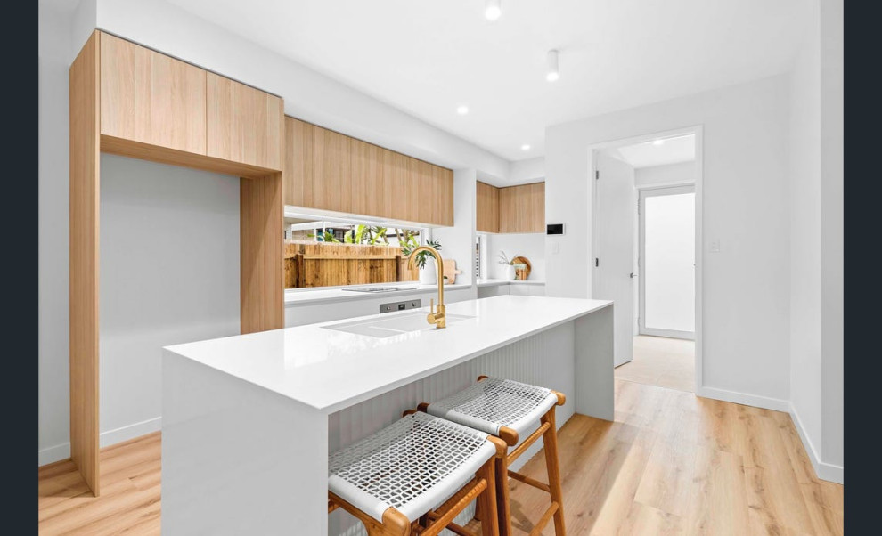 Small beach style galley kitchen in Sunshine Coast with an undermount sink, flat-panel cabinets, light wood cabinets, quartz benchtops, white splashback, mosaic tile splashback, vinyl floors and white benchtop.