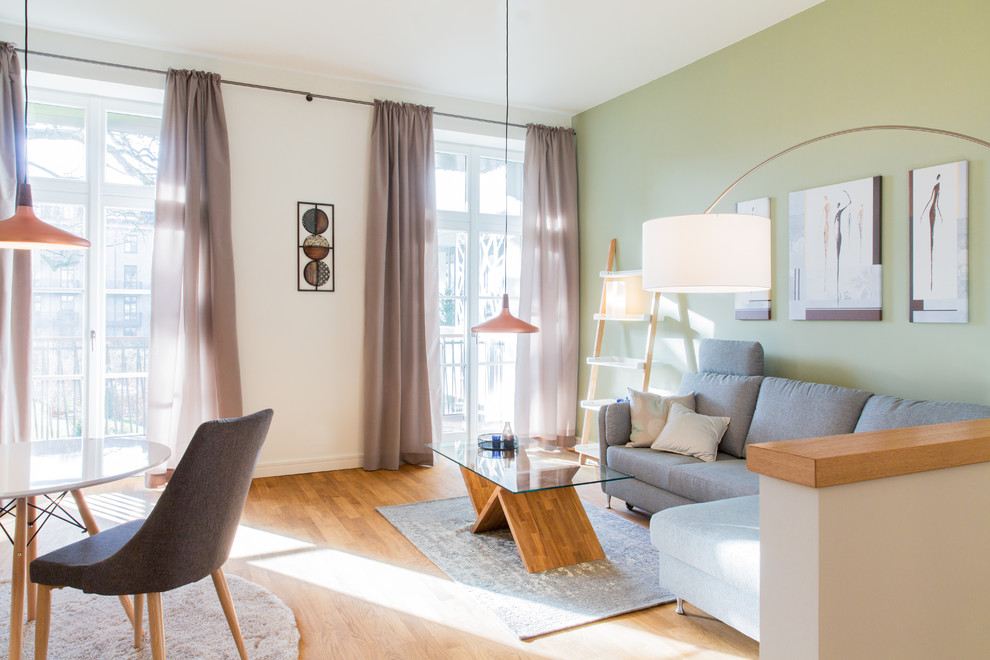 Kleines Modernes Wohnzimmer mit grüner Wandfarbe, braunem Holzboden und braunem Boden in Hamburg