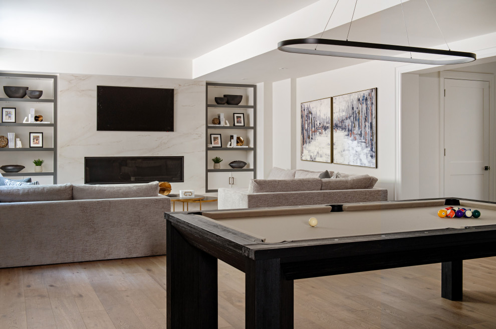 Inspiration for a large transitional walk-out medium tone wood floor basement game room remodel in Toronto with white walls, a standard fireplace and a tile fireplace
