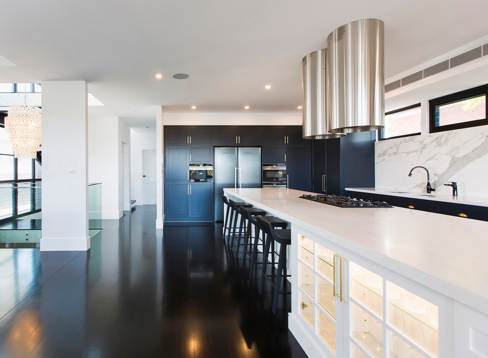 Photo of a large traditional l-shaped eat-in kitchen in Newcastle - Maitland with an undermount sink, shaker cabinets, white cabinets, solid surface benchtops, white splashback, marble splashback, black appliances, painted wood floors, with island, black floor and white benchtop.