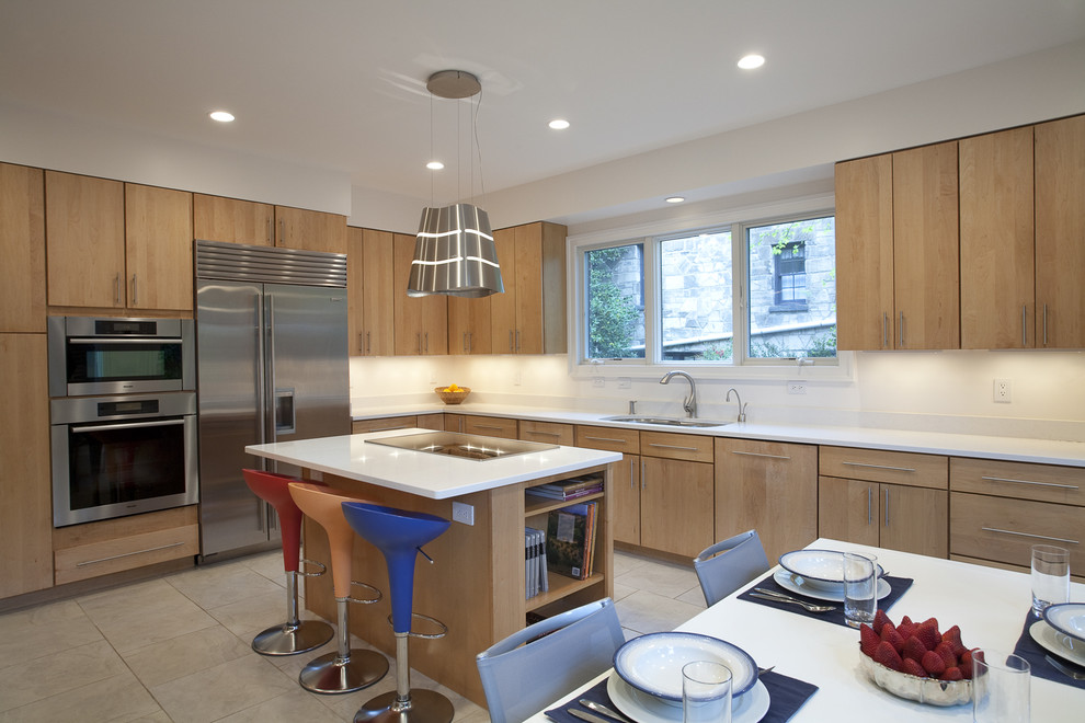 Inspiration for a large eclectic l-shaped eat-in kitchen in DC Metro with stainless steel appliances, a double-bowl sink, flat-panel cabinets, light wood cabinets, solid surface benchtops, travertine floors, with island and beige floor.