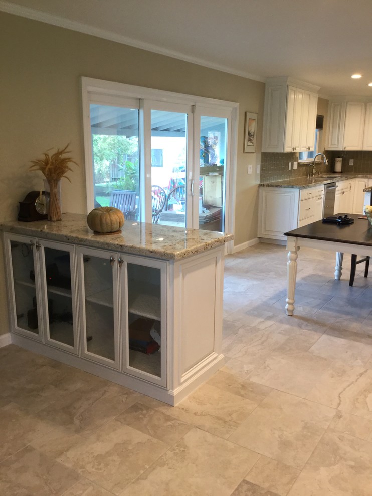 Design ideas for a mid-sized traditional u-shaped eat-in kitchen in San Francisco with a double-bowl sink, flat-panel cabinets, white cabinets, granite benchtops, beige splashback, glass tile splashback, stainless steel appliances, porcelain floors and with island.