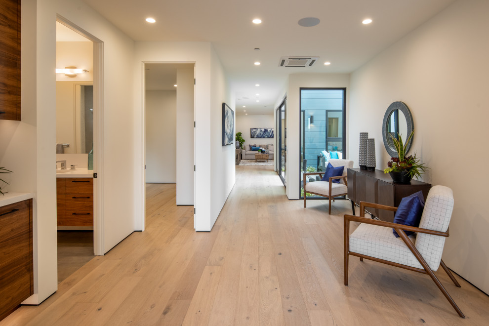 Inspiration for a mid-sized modern foyer in San Diego with white walls, light hardwood floors, a single front door, a medium wood front door and white floor.
