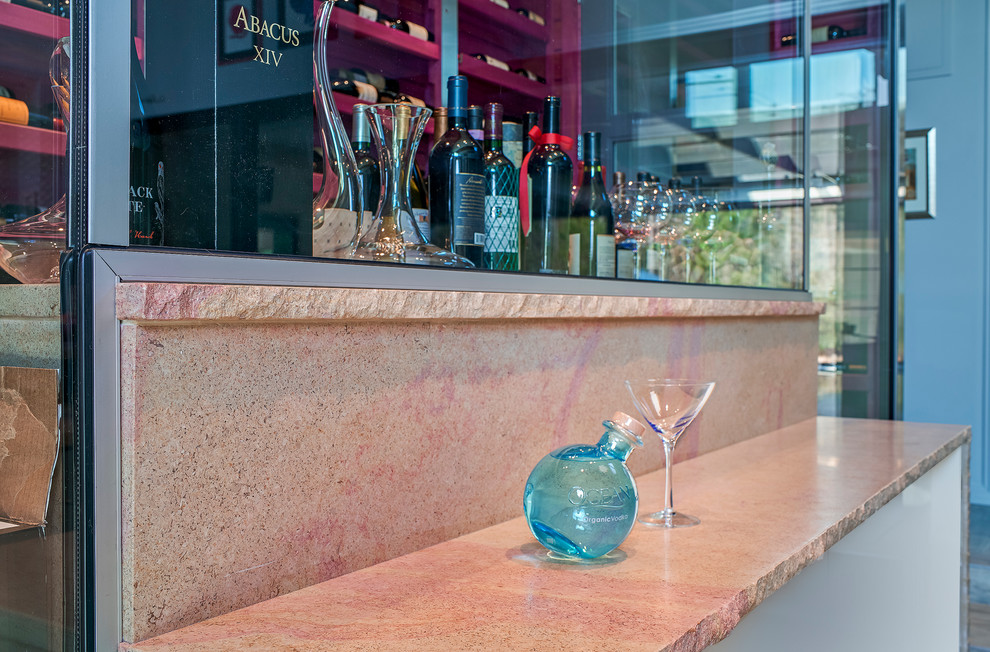 Inspiration for a modern home bar in Charleston with glass-front cabinets, limestone benchtops, beige splashback, glass tile splashback and pink benchtop.