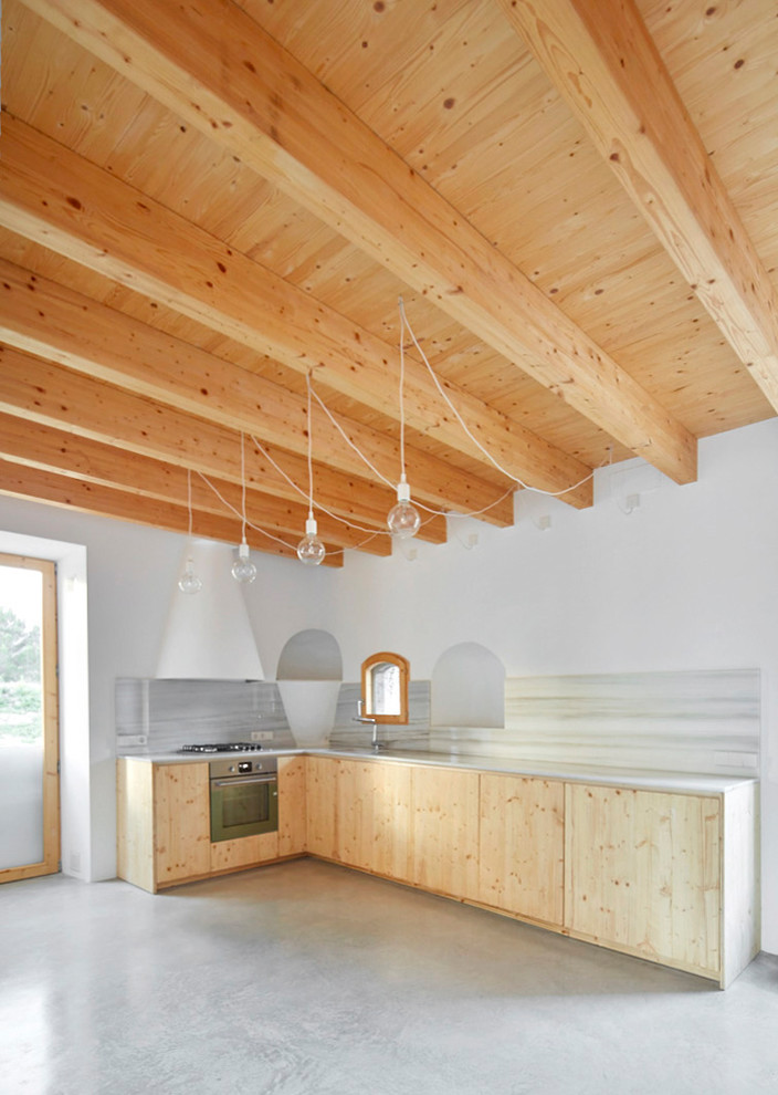 This is an example of a large mediterranean l-shaped open plan kitchen in Barcelona with flat-panel cabinets, light wood cabinets, white splashback, concrete floors, no island and grey floor.