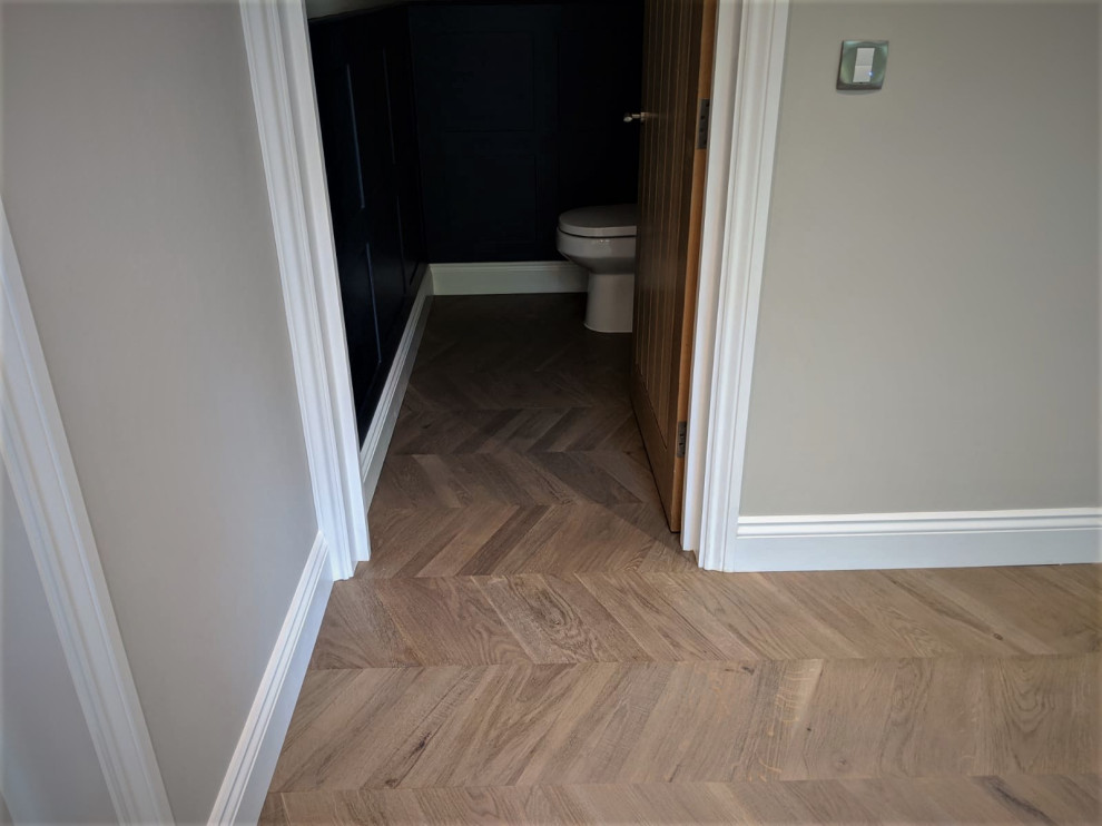 Photo of a contemporary bathroom in Hertfordshire with a one-piece toilet, light hardwood floors and brown floor.