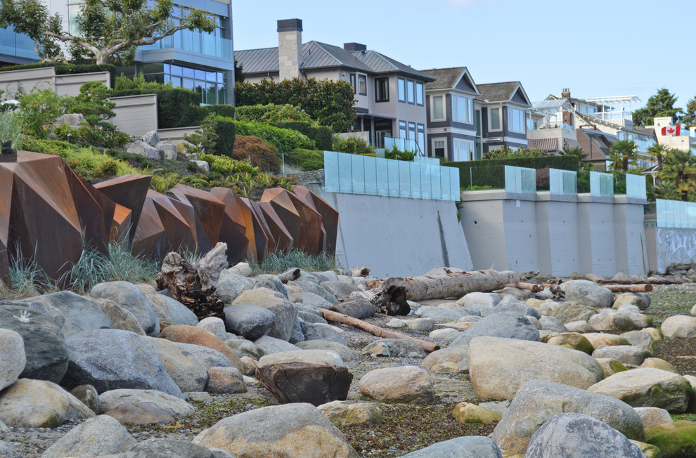 This is an example of a large contemporary sloped full sun garden in Vancouver with a retaining wall.