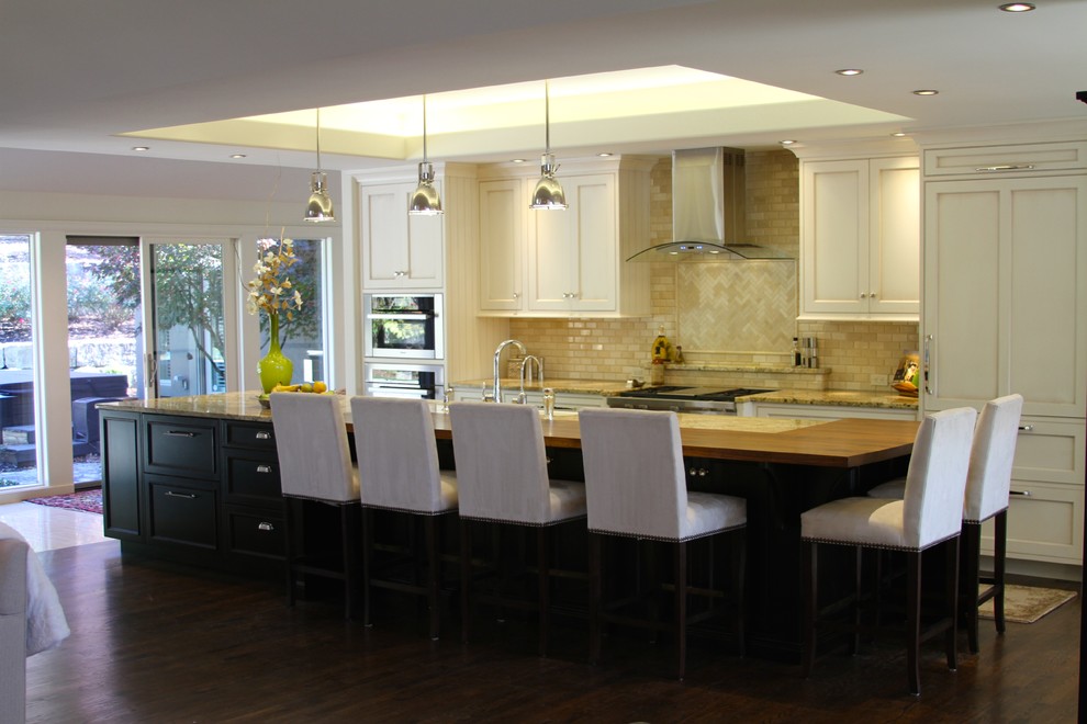 Open concept kitchen - large transitional single-wall dark wood floor and brown floor open concept kitchen idea in Kansas City with a farmhouse sink, recessed-panel cabinets, white cabinets, granite countertops, beige backsplash, paneled appliances, an island and multicolored countertops