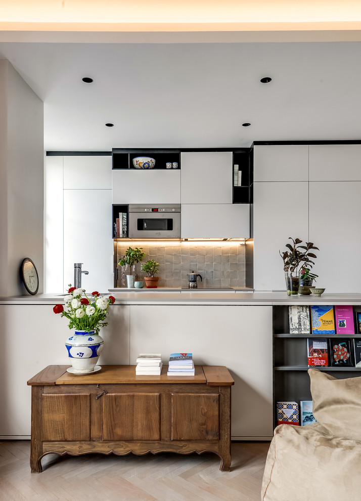 Large eclectic galley open plan kitchen in Paris with white cabinets, grey splashback, terra-cotta splashback, panelled appliances and a peninsula.