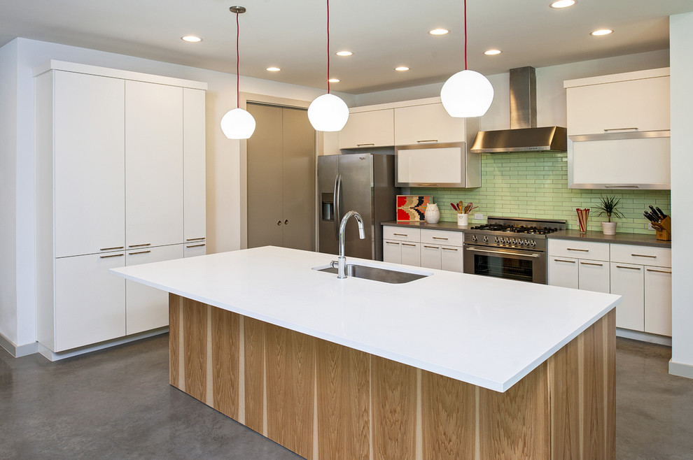 Photo of a contemporary galley kitchen in Austin with an undermount sink, flat-panel cabinets, white cabinets, green splashback, subway tile splashback and stainless steel appliances.