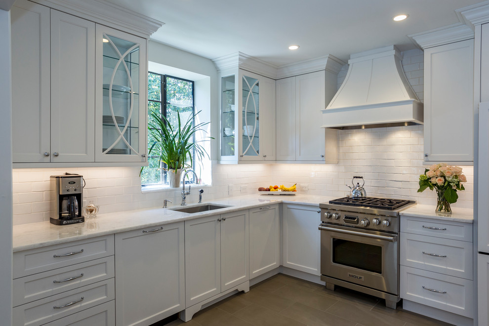Inspiration for a mid-sized transitional u-shaped separate kitchen in Charlotte with an undermount sink, recessed-panel cabinets, white cabinets, marble benchtops, white splashback, stainless steel appliances, porcelain floors, no island, ceramic splashback and beige floor.