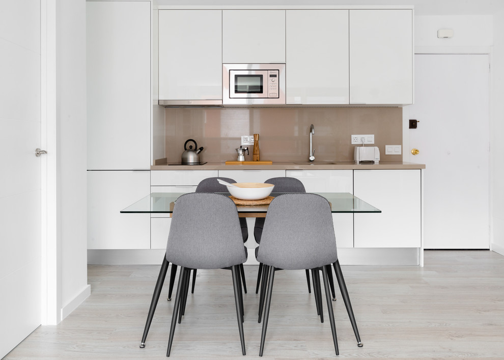 Photo of a scandinavian eat-in kitchen in Other with a single-bowl sink, flat-panel cabinets, white cabinets, brown splashback, light hardwood floors, beige floor and brown benchtop.