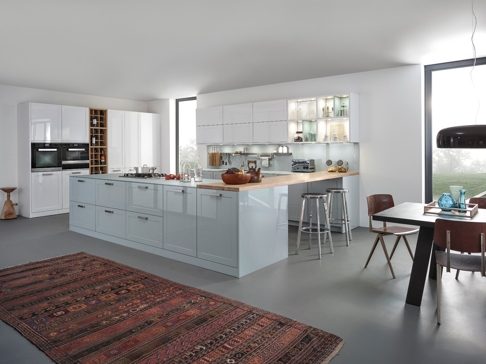 Inspiration for a large contemporary open plan kitchen in Stuttgart with shaker cabinets, blue cabinets, blue splashback, glass sheet splashback, panelled appliances and with island.