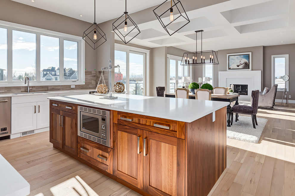Eat-in kitchen - mid-sized transitional galley light wood floor eat-in kitchen idea in Calgary with a drop-in sink, recessed-panel cabinets, medium tone wood cabinets, quartz countertops, gray backsplash, ceramic backsplash, stainless steel appliances and an island
