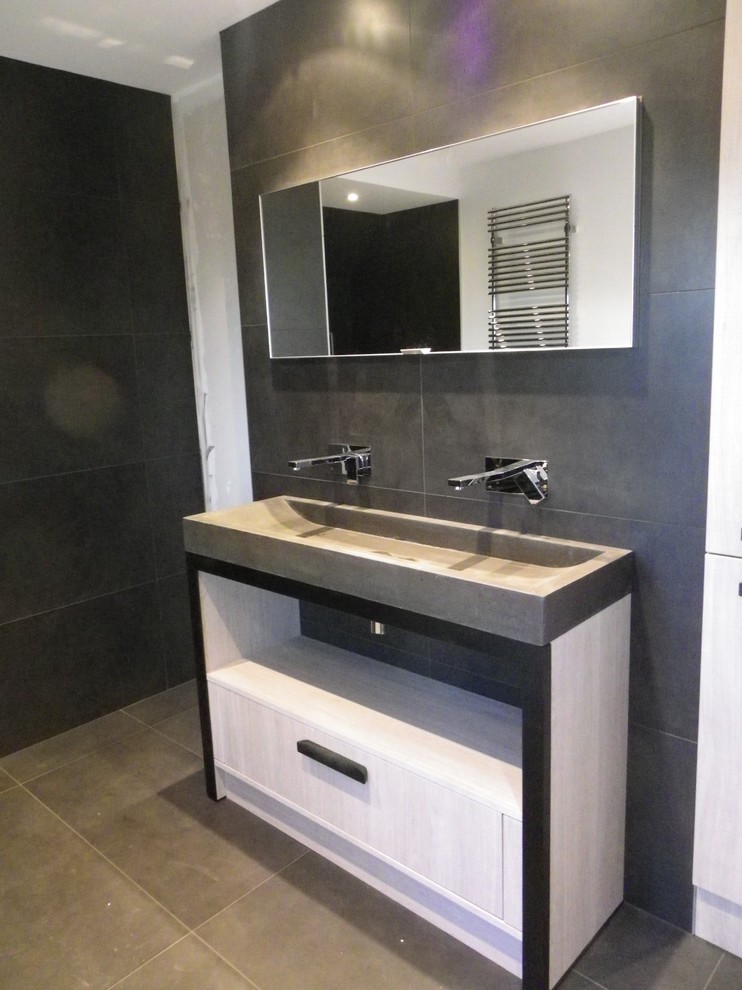 Mid-sized industrial master bathroom in Le Havre with a trough sink, recessed-panel cabinets, light wood cabinets, concrete benchtops, a drop-in tub, a curbless shower, black tile, ceramic tile and black walls.