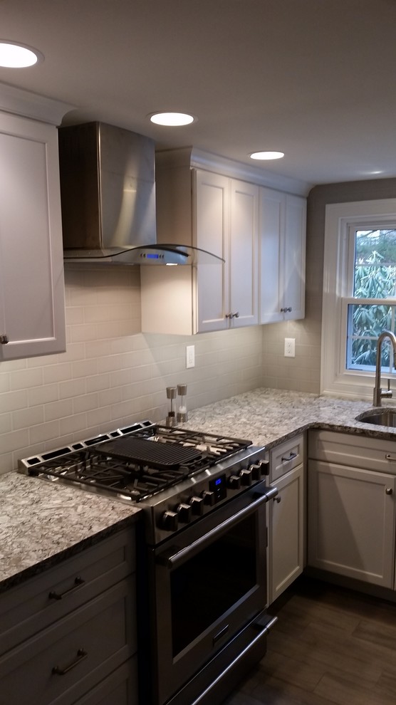 Inspiration for a mid-sized transitional u-shaped porcelain tile and gray floor eat-in kitchen remodel in Boston with an undermount sink, flat-panel cabinets, gray cabinets, quartz countertops, stainless steel appliances, an island, white backsplash, subway tile backsplash and white countertops