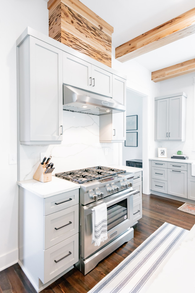 Example of a mid-sized transitional dark wood floor kitchen design with shaker cabinets, white cabinets, quartzite countertops, white backsplash, stone slab backsplash and white countertops