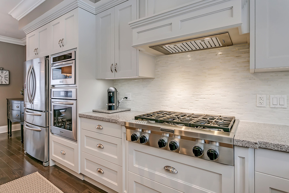 Open concept kitchen - mid-sized transitional l-shaped open concept kitchen idea in Toronto with an undermount sink, recessed-panel cabinets, white cabinets, quartz countertops, white backsplash, matchstick tile backsplash, stainless steel appliances, an island and multicolored countertops