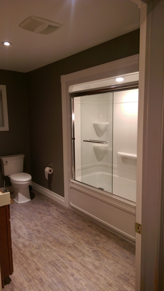 Inspiration for a mid-sized transitional master vinyl floor and multicolored floor alcove bathtub remodel with recessed-panel cabinets, medium tone wood cabinets, a two-piece toilet, gray walls, laminate countertops and yellow countertops