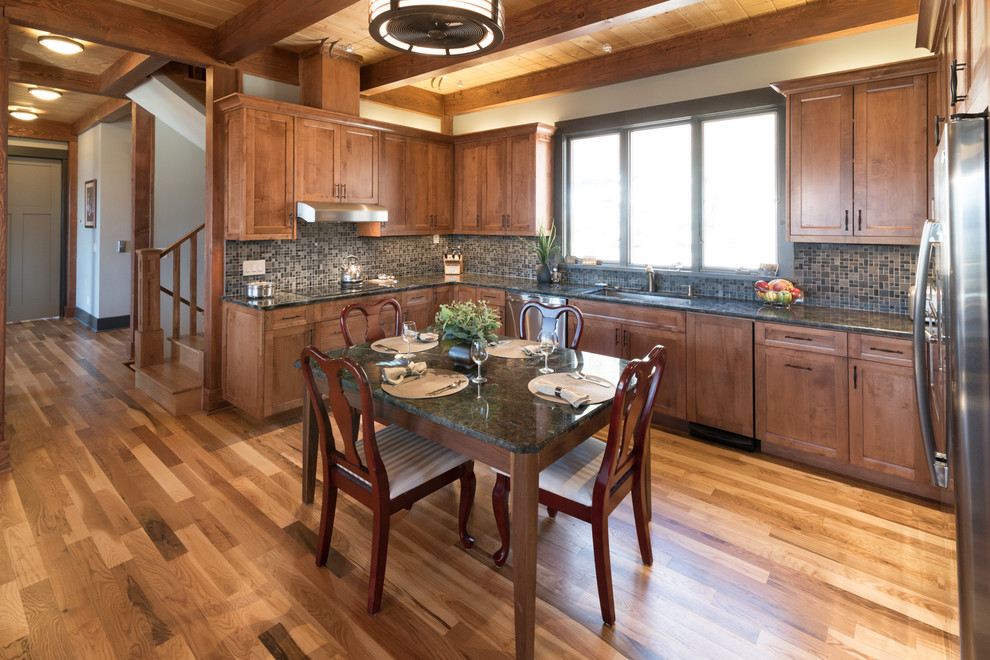 Mountain style u-shaped light wood floor eat-in kitchen photo with an undermount sink, shaker cabinets, medium tone wood cabinets, granite countertops, blue backsplash, glass tile backsplash, stainless steel appliances and no island