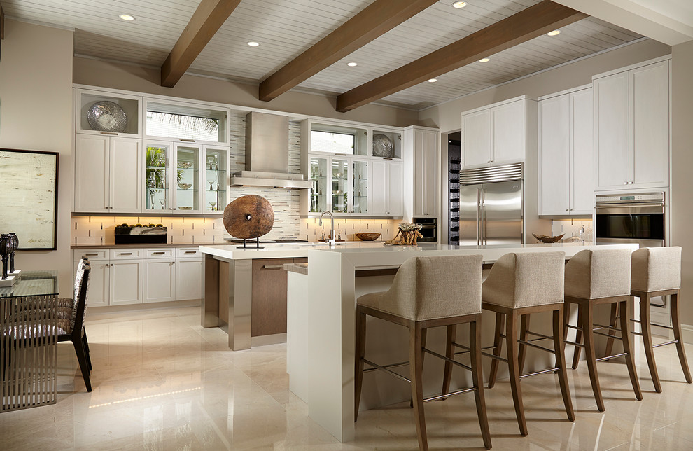 This is an example of a large transitional u-shaped kitchen in Miami with white cabinets, multiple islands, shaker cabinets, beige splashback and stainless steel appliances.