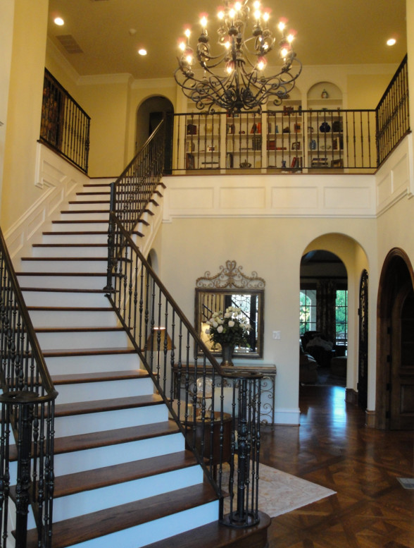 This is an example of a large transitional wood curved staircase in Dallas with wood risers and metal railing.