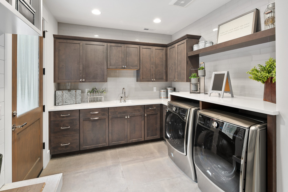 Inspiration for a large arts and crafts l-shaped dedicated laundry room in Seattle with an undermount sink, shaker cabinets, dark wood cabinets, quartzite benchtops, grey splashback, glass tile splashback, white walls, ceramic floors, a side-by-side washer and dryer, grey floor and white benchtop.