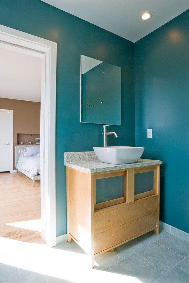 This is an example of a contemporary master bathroom in San Francisco with granite benchtops, a vessel sink, glass-front cabinets, light wood cabinets and blue walls.