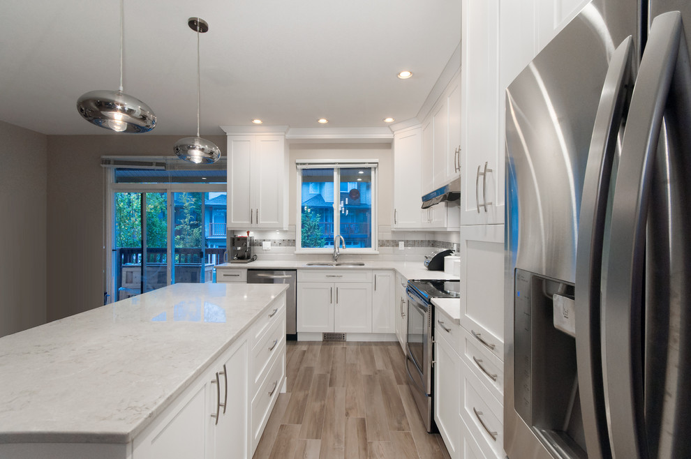 Eat-in kitchen - mid-sized transitional l-shaped light wood floor eat-in kitchen idea in Vancouver with an undermount sink, shaker cabinets, white cabinets, quartz countertops, white backsplash, ceramic backsplash, stainless steel appliances and an island