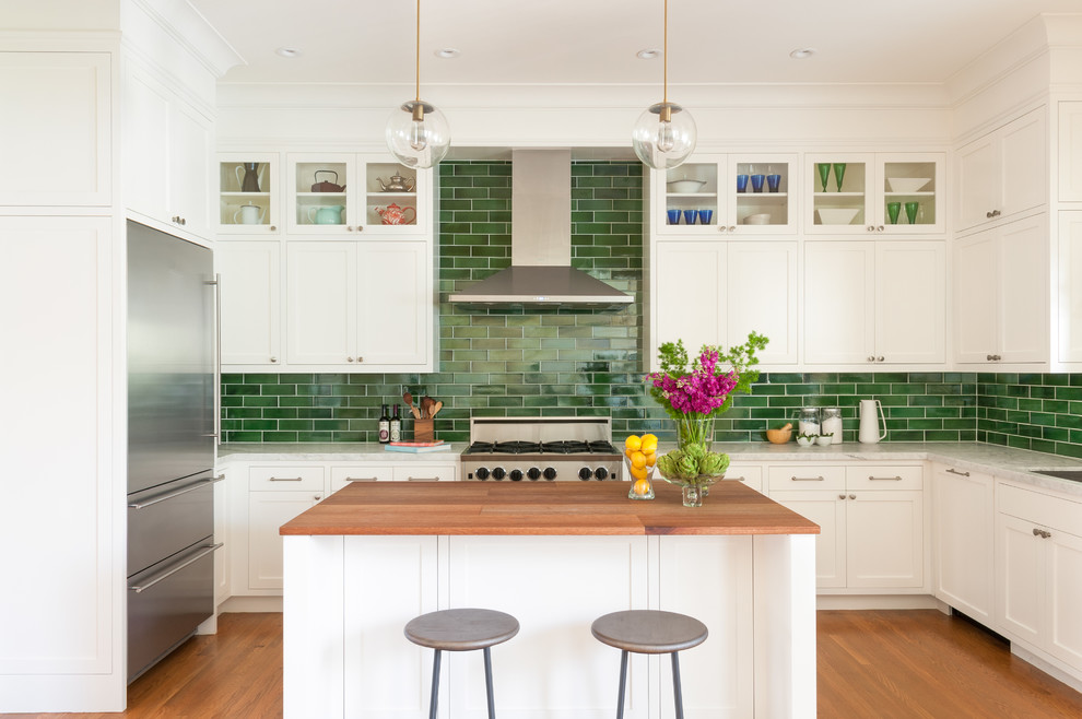 Design ideas for a mid-sized transitional u-shaped kitchen in San Francisco with an undermount sink, shaker cabinets, white cabinets, green splashback, subway tile splashback, stainless steel appliances, medium hardwood floors, with island, marble benchtops and brown floor.