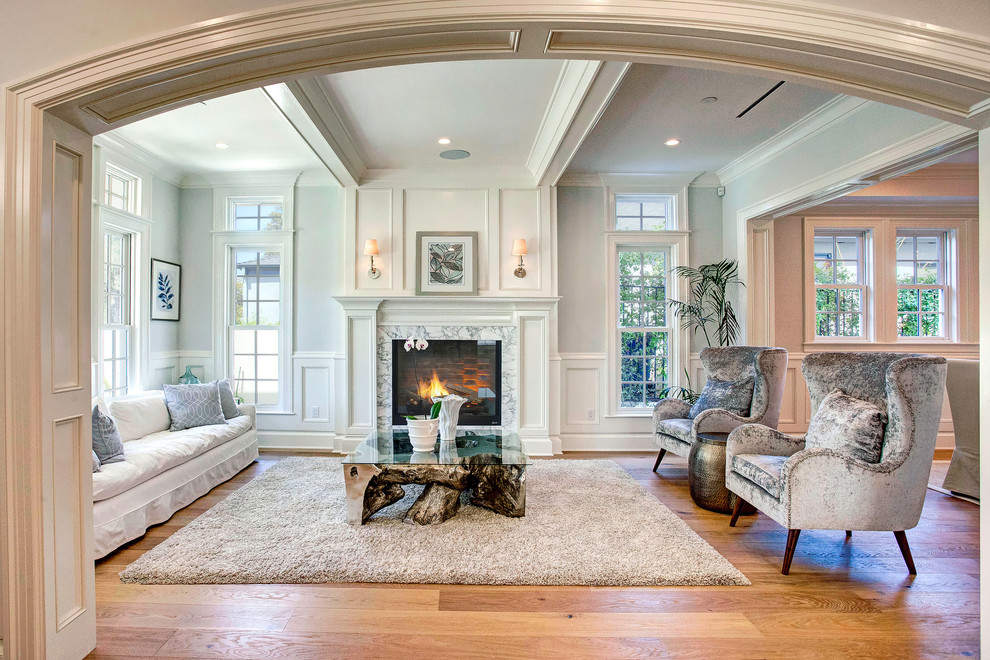 Photo of a large transitional open concept living room in Los Angeles with white walls, a standard fireplace, no tv, medium hardwood floors and a wood fireplace surround.