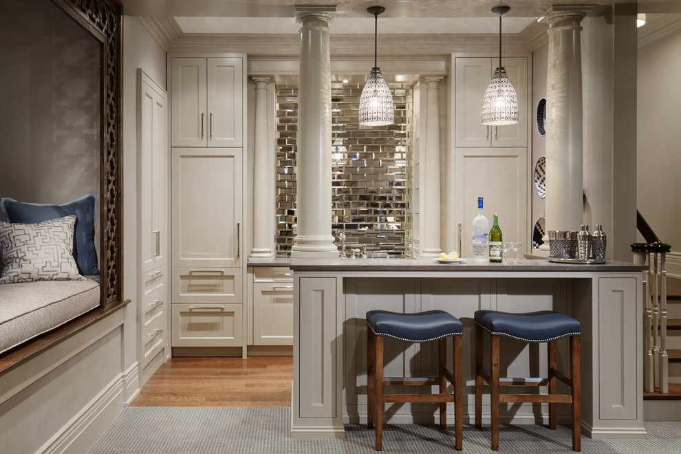 Inspiration for a large traditional u-shaped wet bar in Chicago with shaker cabinets, white cabinets, mirror splashback, medium hardwood floors and quartz benchtops.