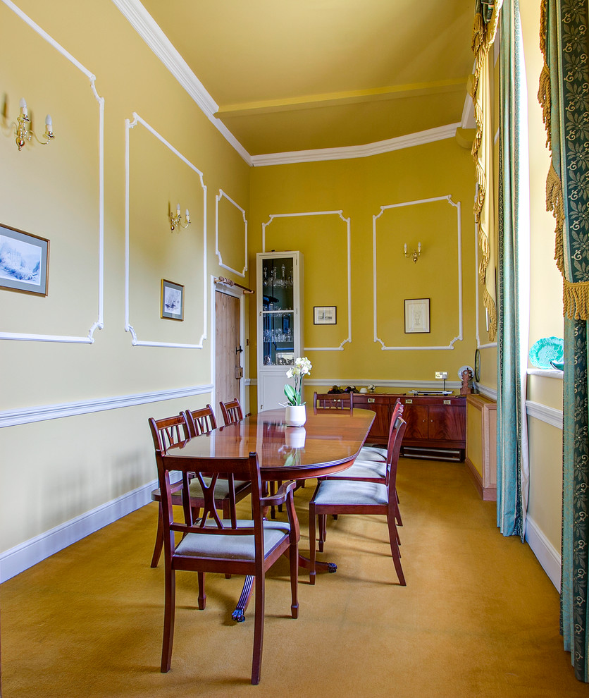 Inspiration for a traditional separate dining room in Surrey with yellow walls and carpet.