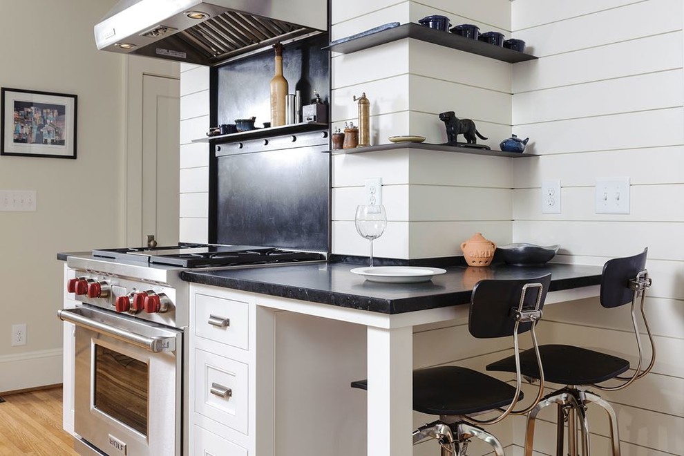 Example of a mid-sized transitional l-shaped light wood floor kitchen pantry design in Denver with recessed-panel cabinets, black cabinets, laminate countertops, black backsplash, cement tile backsplash, stainless steel appliances and no island