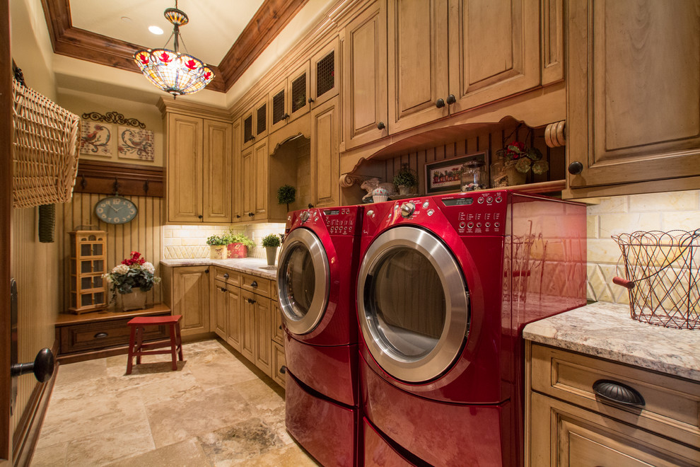 Inspiration for a large mediterranean single-wall dedicated laundry room in Salt Lake City with raised-panel cabinets, medium wood cabinets, granite benchtops, beige walls, travertine floors, a side-by-side washer and dryer and brown floor.