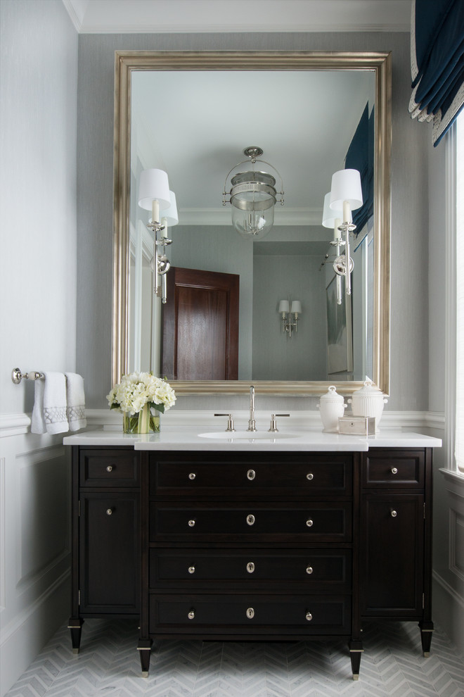 Small transitional powder room in New York with furniture-like cabinets, dark wood cabinets, gray tile, white tile, mosaic tile, grey walls, marble floors, an undermount sink, engineered quartz benchtops and white benchtops.
