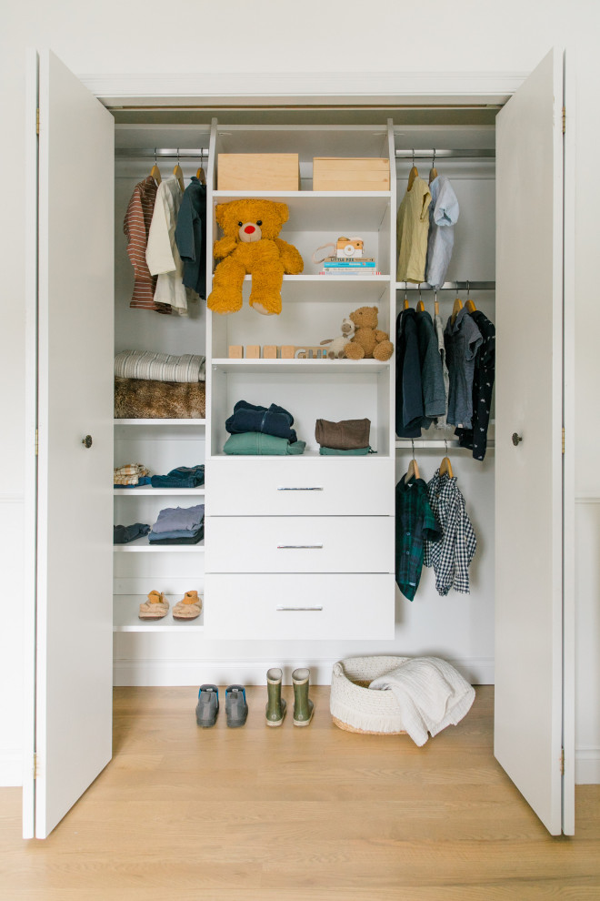Photo of a small transitional built-in wardrobe in Other with flat-panel cabinets, white cabinets and light hardwood floors.